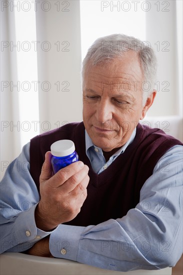 Senior man reading label on medicine bottle. Photo : Rob Lewine