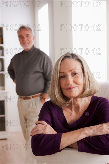 Portrait of smiling senior woman, senior man in background. Photo : Rob Lewine