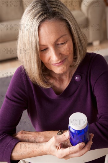 Senior woman reading label on medicine bottle. Photo : Rob Lewine