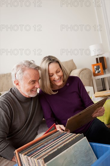 Smiling senior couple looking at vinyl's in living room. Photo : Rob Lewine