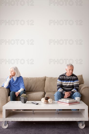 Angry senior couple sitting on sofa. Photo : Rob Lewine