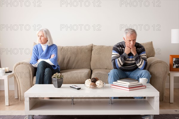 Angry senior couple sitting on sofa. Photo : Rob Lewine