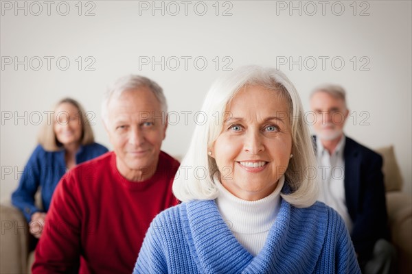 Two senior couples on sofa, smiling woman in foreground. Photo : Rob Lewine