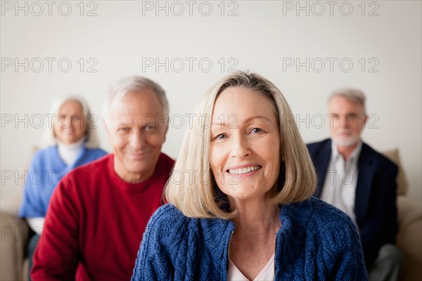 Two senior couples on sofa, smiling woman in foreground. Photo : Rob Lewine