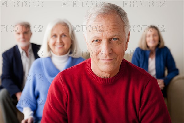 Two senior couples on sofa, smiling man in foreground. Photo : Rob Lewine