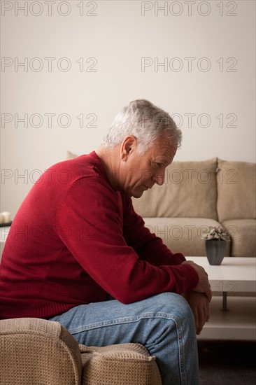 Sad senior man sitting on armchair. Photo : Rob Lewine