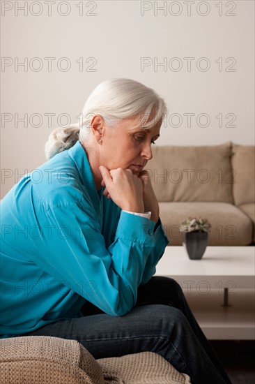 Sad senior woman sitting on armchair. Photo : Rob Lewine