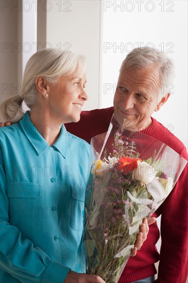 Senior couple, woman holding flowers. Photo : Rob Lewine