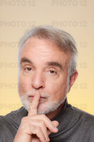 Studio shot of senior man with finger on her lips. Photo : Rob Lewine
