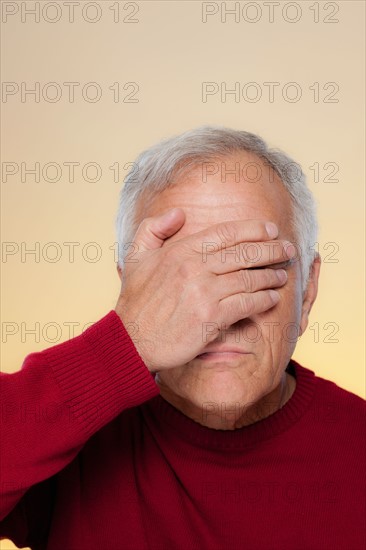 Studio shot of senior man covering eyes. Photo : Rob Lewine