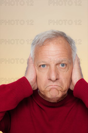 Studio shot of senior man covering ears. Photo : Rob Lewine
