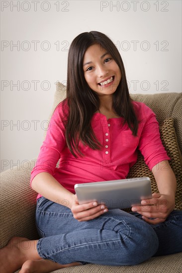 Portrait of smiling girl (12-13) using digital tablet. Photo : Rob Lewine