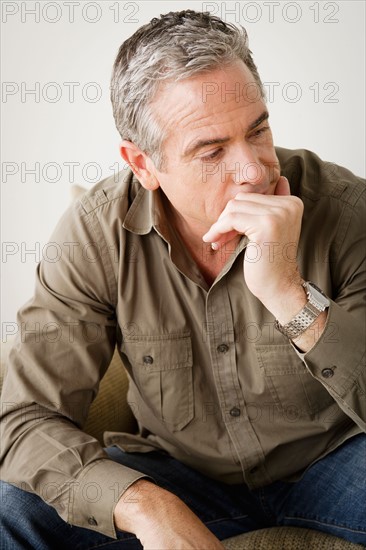 Worried mature man sitting on sofa. Photo : Rob Lewine