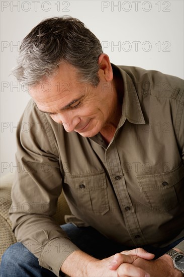 Worried mature man sitting on sofa. Photo : Rob Lewine