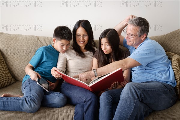 Family watching photo album together. Photo : Rob Lewine