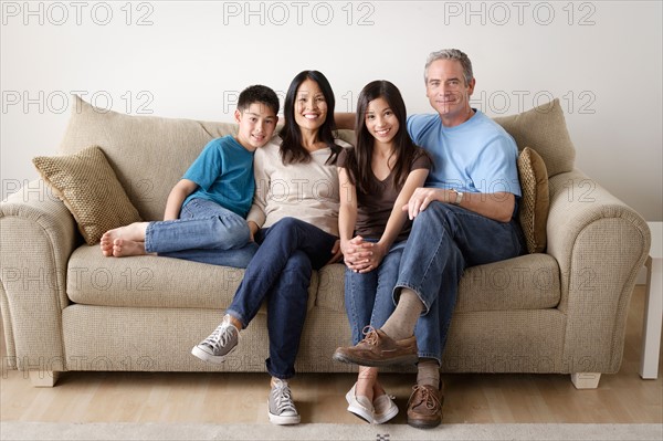 Cheerful family sitting on sofa. Photo : Rob Lewine