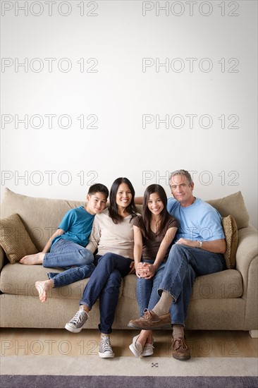 Cheerful family sitting on sofa. Photo : Rob Lewine