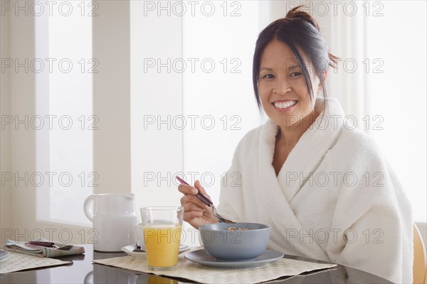 Woman in bathrobe having cereal for breakfast. Photo : Rob Lewine