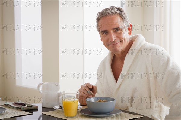 Man in bathrobe having cereal for breakfast. Photo : Rob Lewine