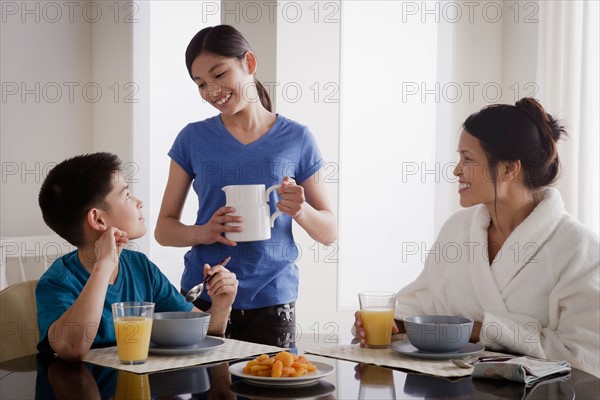 Girl serving milk to family over breakfast. Photo : Rob Lewine