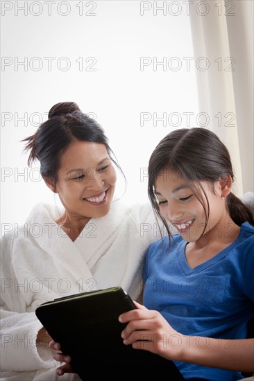 Mother embracing daughter using laptop. Photo : Rob Lewine