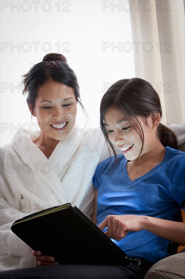 Mother embracing daughter using laptop. Photo : Rob Lewine