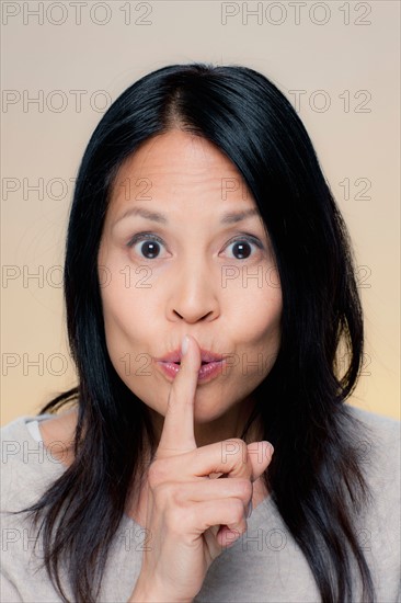 Portrait of woman making silence gesture. Photo : Rob Lewine