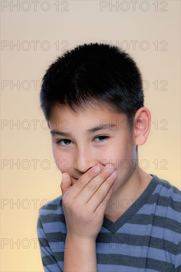 Portrait of laughing boy covering mouth with hand. Photo : Rob Lewine