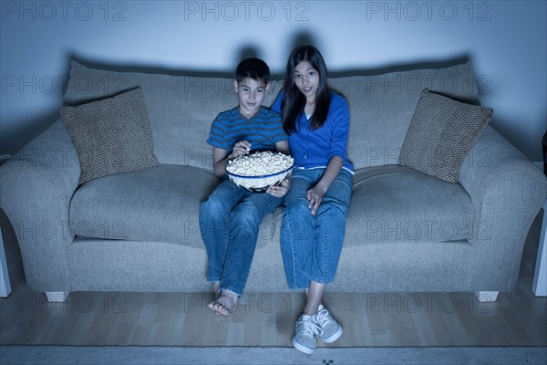 Brother and sister (10-11, 12-13) watching television. Photo : Rob Lewine