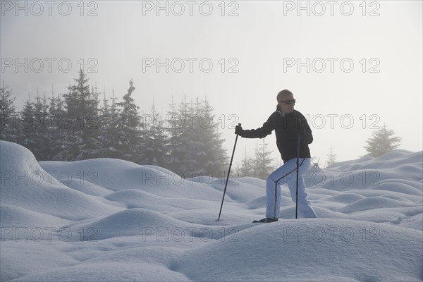 Austria, Maria Alm. Young woman hiking in winter scenery. Photo : Mark de Leeuw