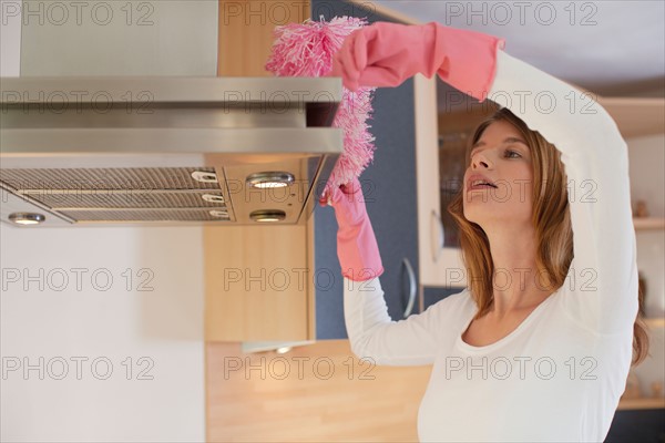 Young woman cleaning kitchen. Photo : Mark de Leeuw