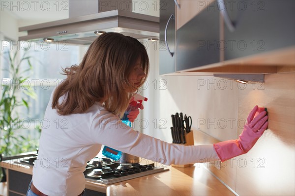 Young woman cleaning the kitchen. Photo : Mark de Leeuw