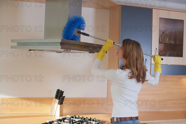 Young woman cleaning the kitchen. Photo : Mark de Leeuw