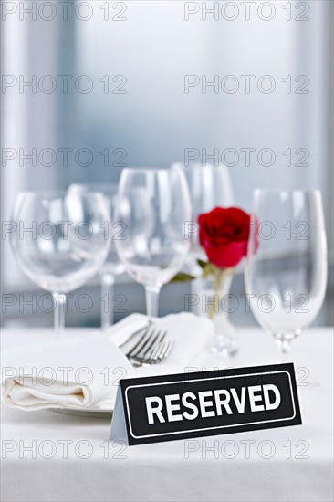 Dishes and cutlery prepared for meal in restaurant with reserved sign. Photo : Elena Elisseeva