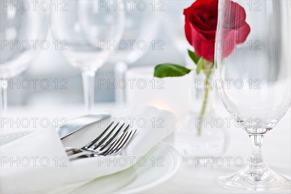 Dishes and cutlery prepared for meal decorated with red rose. Photo : Elena Elisseeva