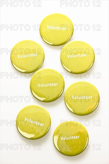 Close-up studio shot of yellow volunteer badges on white background. Photo : Elena Elisseeva