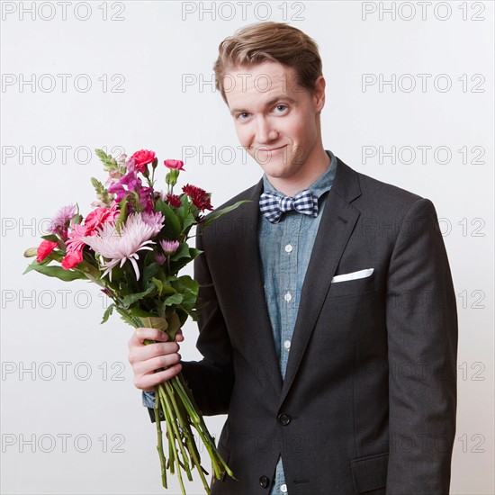 Portrait of young handsome man holding bunch of flowers. Photo : Jessica Peterson