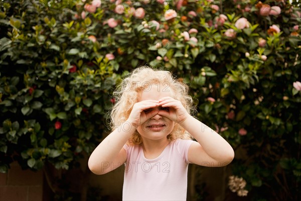 Cute blonde girl (4-5) looking through imaginary binoculars. Photo : Jessica Peterson