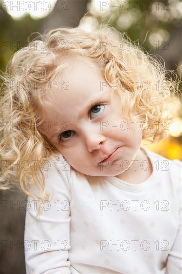 Outdoor portrait of cute blonde girl (4-5) making face. Photo : Jessica Peterson