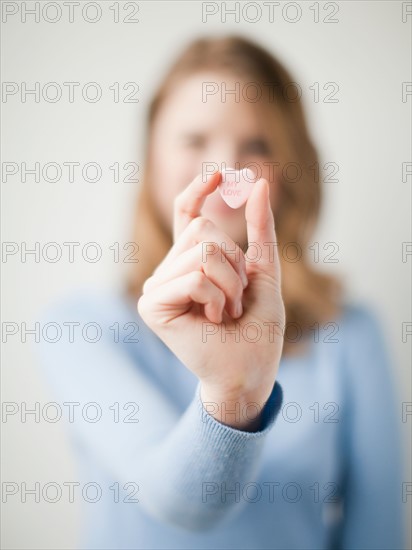 Young attractive woman showing heart with love inscription. Photo : Jessica Peterson