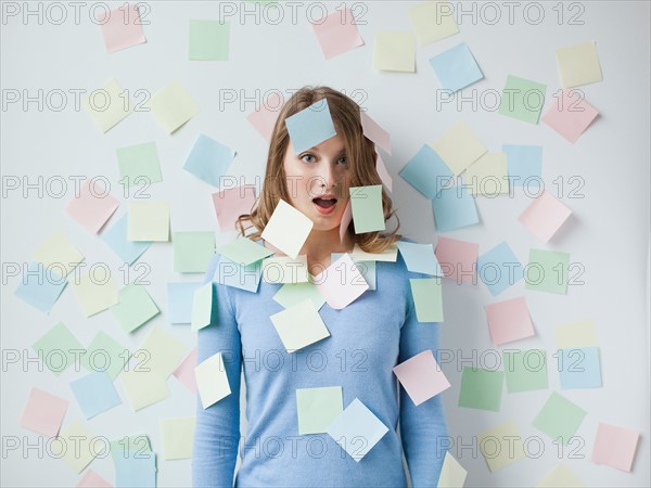 Indoor portrait of young attractive woman standing in f front of wall covered in adhesive notes. Photo : Jessica Peterson