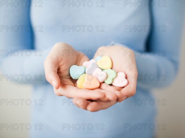 Young woman showing handful of cookie hearts. Photo : Jessica Peterson