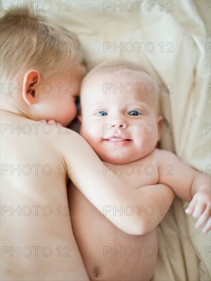 Happy young boy (2-3) embracing baby brother (6-11 months). Photo : Jessica Peterson