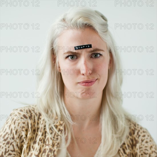 Portrait of young woman with word stupid on forehead. Photo : Jessica Peterson