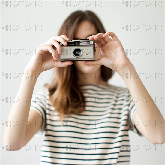 Studio shot of young woman with old-fashioned camera. Photo : Jessica Peterson