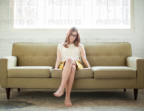 Young woman sitting on sofa. Photo : Jessica Peterson