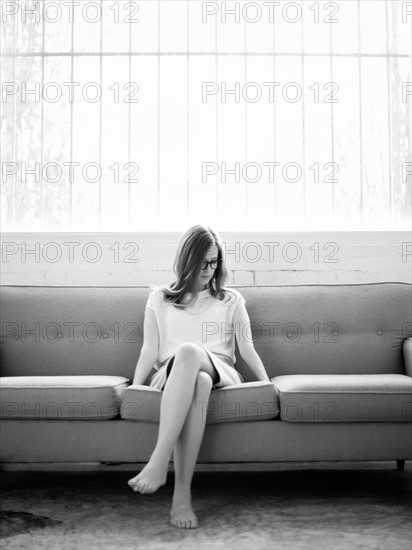 Young woman sitting on sofa. Photo : Jessica Peterson