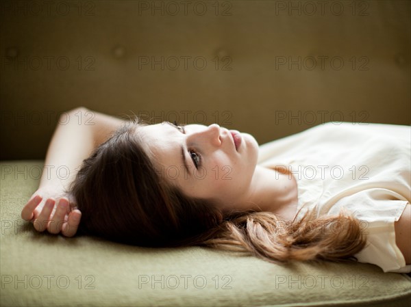 Young woman relaxing on sofa. Photo : Jessica Peterson