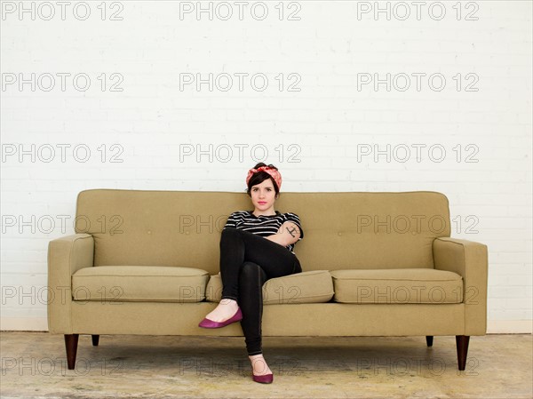 Young woman sitting on sofa. Photo : Jessica Peterson