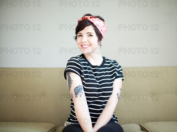 Young woman sitting on sofa. Photo : Jessica Peterson